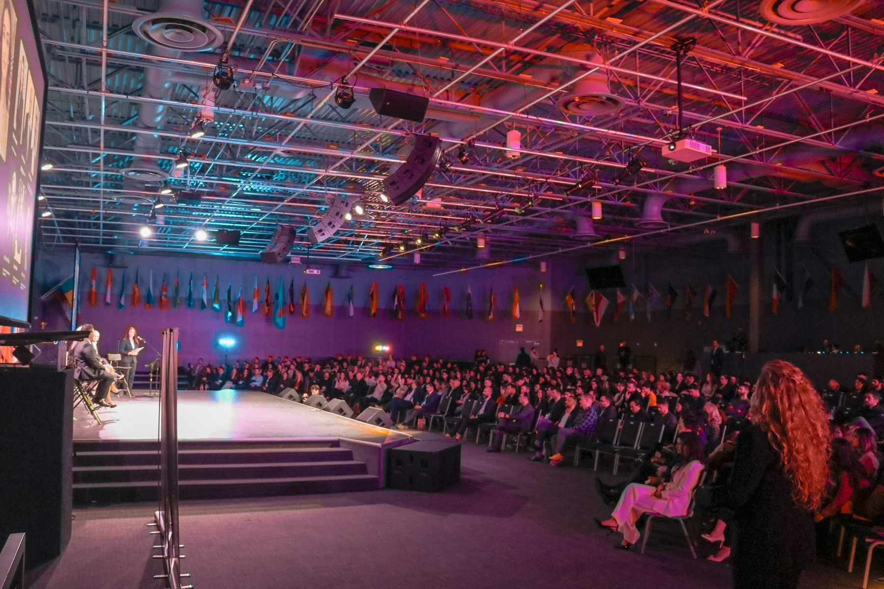 A large audience seated before a stage at a conference produced by the team